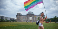 Ein Mann rennt mit Regenbogenflagge am Reichstag vorbei.