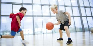 Zwei Jungen beim Dribbeln mit dem Basketball in der Halle