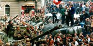 Menschenmenge mit Fahne umringt einen Panzer