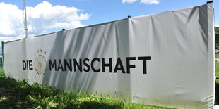 Ein Radfahrer vor einem Plakat auf dem steht „Die Mannschaft - Herzlich Willkommen“