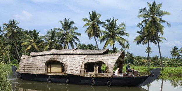 Ein Boot auf einem indischen Fluss, im Hintergrund Palmen
