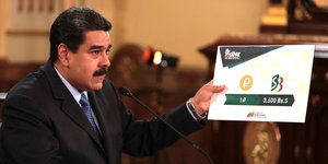 Venezuelas Präsdent Maduro hält ein Schild in der Hand, auf dem steht, dass ein Petro zukünftig 3 600 Bolivar kostet.