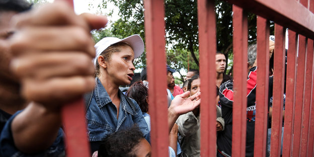 Menschen stehen in Brasilien vor einem Zaun.