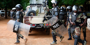 Mehrere Polizisten in Kampfmontur vor einem Pick-Up