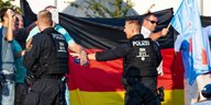 Zwei Polizisten und Demonstranten mit Deutschland-Fahnen