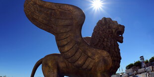 Der Löwe als Statue, dahinter blauer Himmel und Sonne