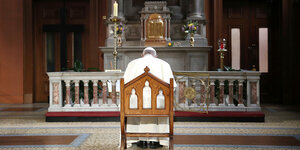 Der Papst von hinten - in einem Stuhl sitzend vor dem Altar in einem Kirchenraum
