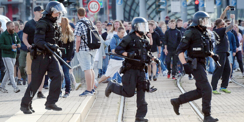 Polizisten laufen durch die Stadt, dahinter Passanten