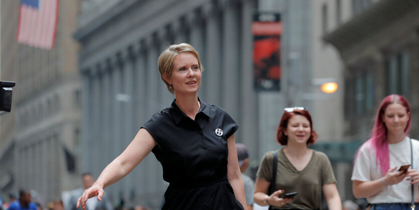 Cynthia Nixon läuft durch die Straßen, hinter ihr die US-Flagge und zwei Frauen