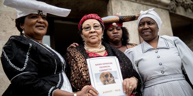 Herero- und Nama-Aktivistinnen stehen nebeneinander und halten ein Report