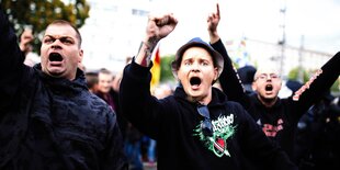 Rechte Demonstranten schreien mit erhobener Faust in Richtung Kamera