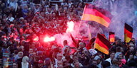 Demonstranten der rechten Szene zünden Pyrotechnik und schwenken Deutschlandfahnen