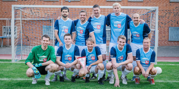 Ein gemischtgeschlechtliches Fußballteam in blauen Triktos.