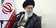 Ajatollah Ali Chamenei vor Iranflagge und Mikrofon