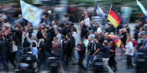 Eine Gruppe demonstrierender Menschen. Einige schwenken Deutschlandflaggen oder tragen schwarz-rot-goldene Regenschirme