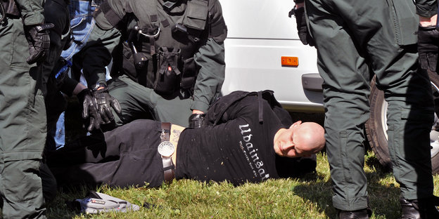 Ein Mann wird von mehreren Polizisten am Boden fixiert