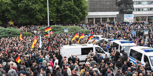 Menschen mit Deutschlandflaggen ziehen vor das Karl-Marx-Denkmal in Chemnitz