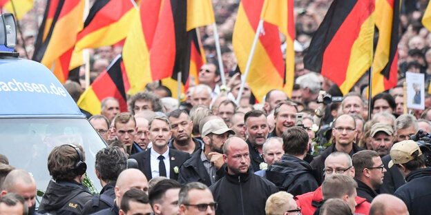 Björn Höcke inmitten einer Menschenmenge, im Hintergrund viele Deutschlandflaggen
