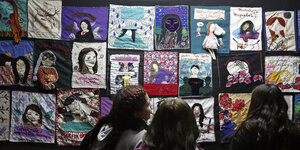 Studentinnen sehen sich ein Kunstwerk mit Gesichtern von ermordeten Frauen an der Technischen Universität von Santiago de Chile an