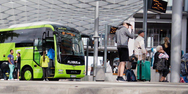 Ein Busbahnhofe mit Reisegästen und einem Flixbus