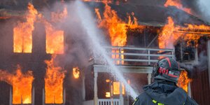 Ein Feuerwehrmann löscht ein brennendes Haus