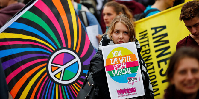 In Chemnitz stegt eine Frau zwischen bunten Fahnen