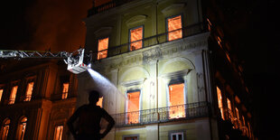 Ein brennendes Gebäude, davor ein Kran der Feuerwehr