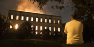 Ein Mann steht vor einem brennenden Gebäude