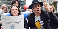 Eine Frau hält ein Schild gegen Antisemitismus hoch, das sich an die Parteiführung richtet, ein Mann daneben trägt eine Davidsternkette
