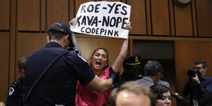 Frau hält ein Protestschild gegen Kavanaugh hoch