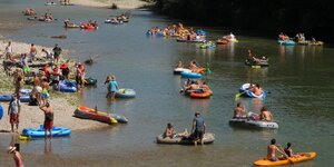 Viele Schlauchboote mit Menschen auf einem Fluss