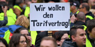 Demonstranten halten ein Schild hoch, auf dem steht: "Wir wollen den Tarifvertrag".