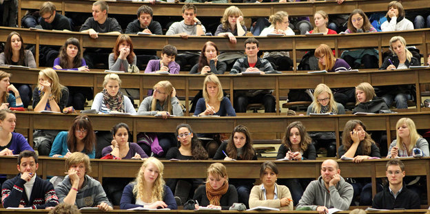 Viele Studenten und Studentinnen sitzen in einem Hörsaal in einer Universität