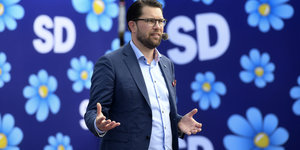 Schwedendemokraten-Chef Jimmie Åkesson spricht vor einer geblümten Werbewand mit Parteilogo