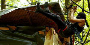 Im Hambacher Forst hängt ein Mensch an einem Seil vom Baum