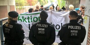 Drei Polizisten stehen vor AktivistInnen der Aktion Unterholz