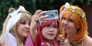 Drei Frauen in Mangakostümen machen ein Selfie