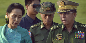 Myanmars Außenministerin Aung San Suu Kyi läuft neben zwei Militärs