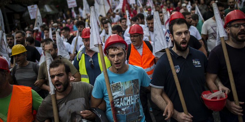 Demonstranten mit Fahnen und Helmen