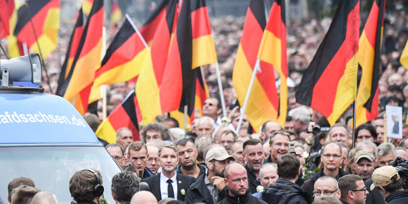 Bernd Höcke in einem Meer von Menschen und Deutschlandfahnen, ein laster daneben verkündet „www.afdsachsen.de“