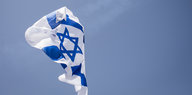 Eine israelische Flagge weht vor blauem Himmel