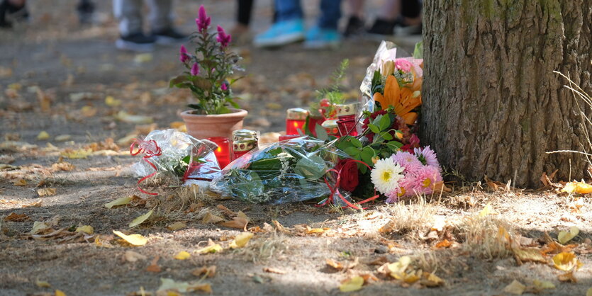 Blumen und Kerzen stehen an einem Baum