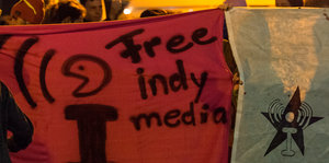 Auf einem Transparent steht "Free Indymedia"