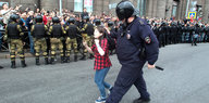 Ein Polizist zieht ein Mädchen an ihren Haaren