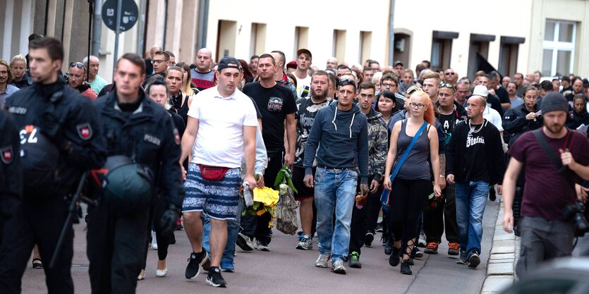 Menschen laufen über eine Straße, flankiert von Polizisten