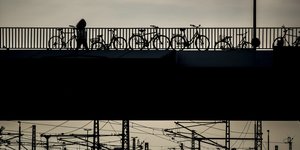 eine Frau läuft in Berlin einsam über eine Brücke in der Dämmerung