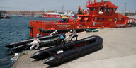 Zwei schwarze Schlauchboote vor einem orange farbenen Grenzschutzschiff