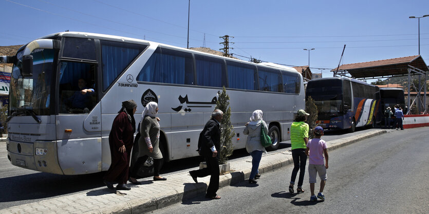 Ein Reisebus, davor mehrere Personen.