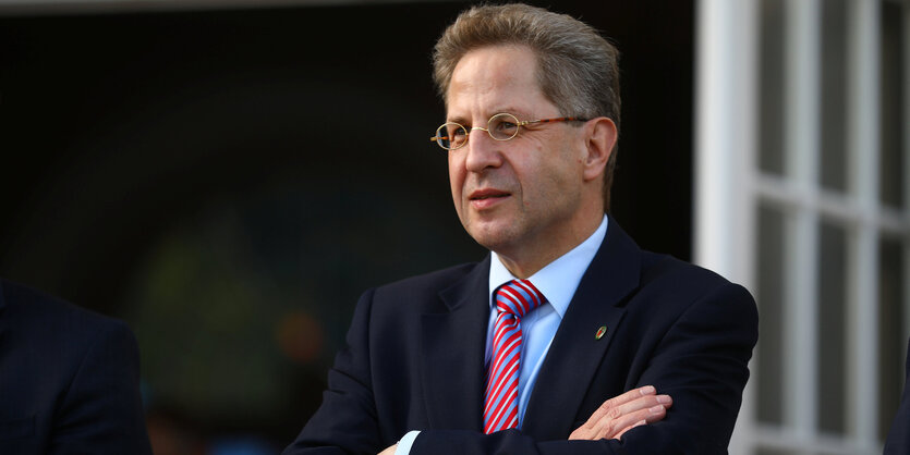 Der Präsident des Verfassungsschutz Hans-Georg Maaßen steht mit verschränkten Armen in einem Anzug mit Krawatte da