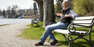 Ein älterer Herr sitzt auf einer Parkbank